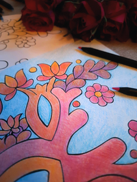 Colorful tree of life drawing on paper with flowers and leaves, surrounded by red roses.